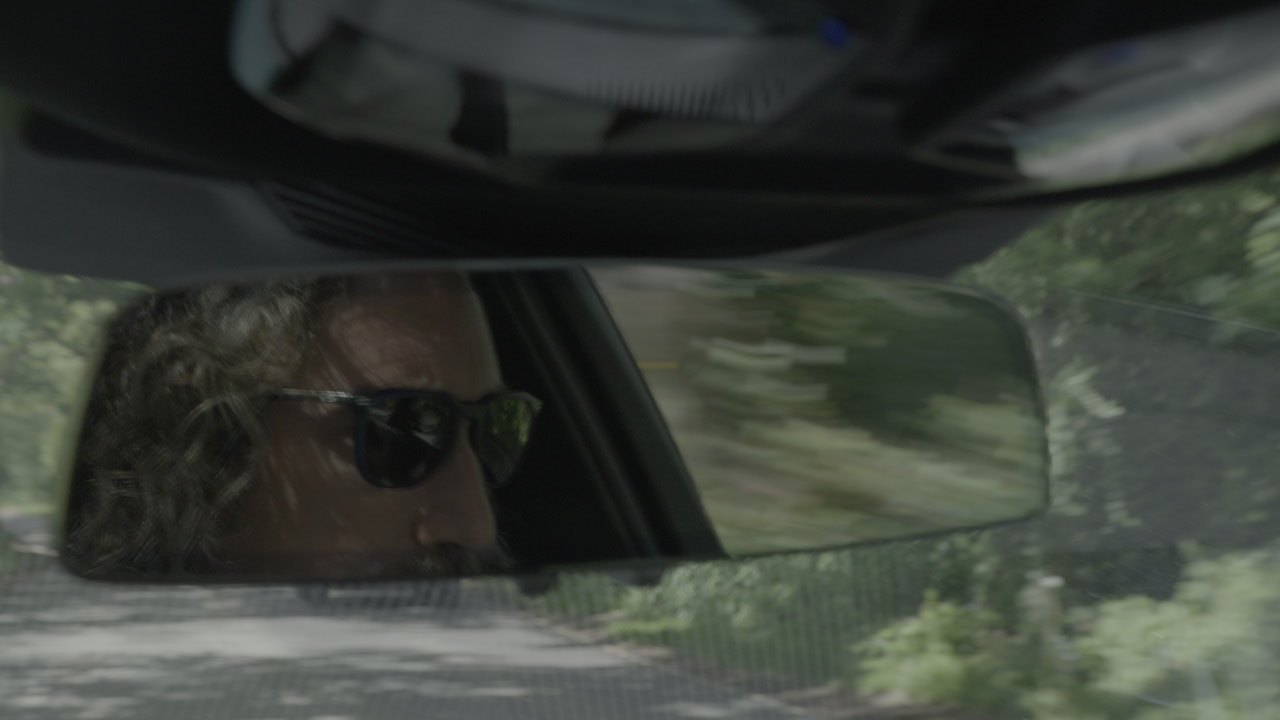 Andy Hooper driving, seen in the rear-view mirror